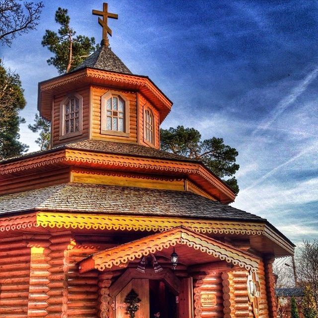 low angle view, architecture, building exterior, built structure, religion, place of worship, spirituality, sky, church, temple - building, cloud - sky, cross, cloud, high section, ornate, outdoors, tree, no people