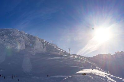 A helicopter flying into the sun, above the ski slopes in les arcs