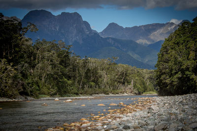 Scenic view of river by mountains against sky