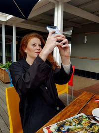 Young woman using mobile phone at table