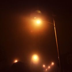 Low angle view of illuminated street light against sky