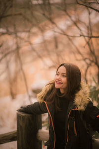 Young woman looking away while standing in winter