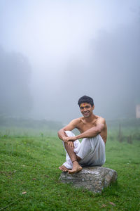 Young handsome asian model sitting in the mountains wearing a dhoti in the morning time.