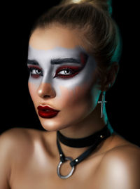 Close-up portrait of a young woman over black background