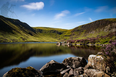 Scenic view of lake by mountain against sky