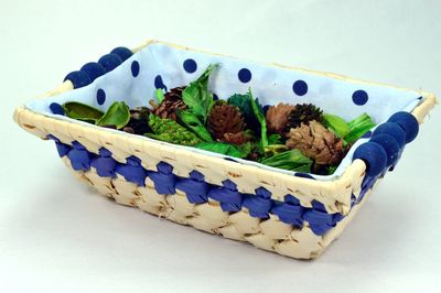 Dried flowers and pine cones in wicker basket over white background