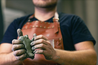 Midsection of sculptor holding clay