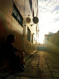 Man sitting in town square against sky