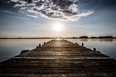 Wooden pier over lake against sky during sunset