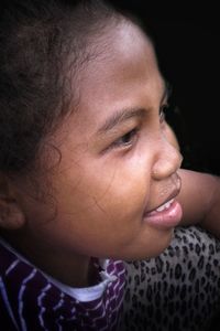 Close-up of girl looking away against black background