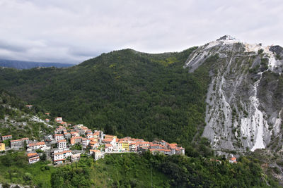 Scenic view of town by mountain against sky