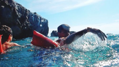 People swimming in pool by sea against sky