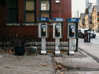 Abandoned television sets by telephone booths on city street against building