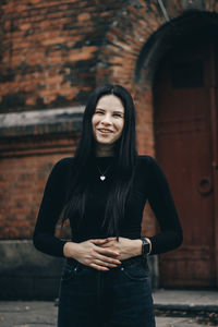 Smiling young woman standing against wall