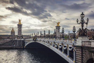 Bridge over river against cloudy sky