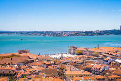 High angle view of townscape by sea against clear blue sky