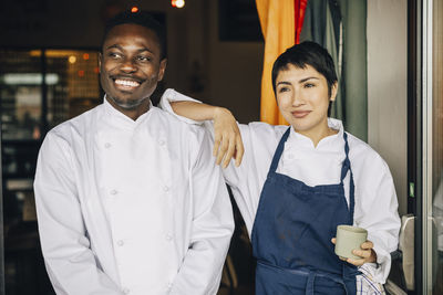 Female chef with hand on shoulder of male colleague standing at doorway