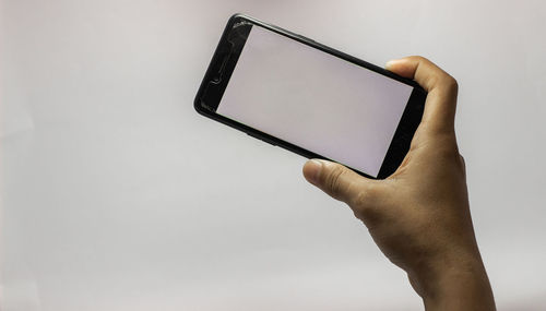 Low section of person holding smart phone against white background