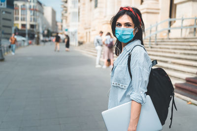 Portrait of young woman standing on road in city