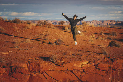 A woman with a phone is jumping in monument valley, arizona