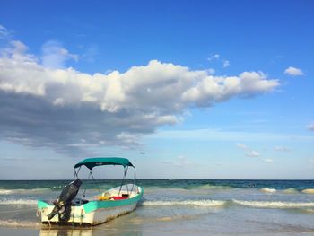 Motorboat at beach against cloudy sky