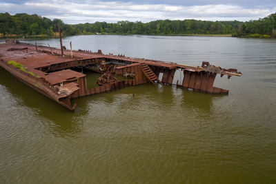 Abandoned boat on river against sky