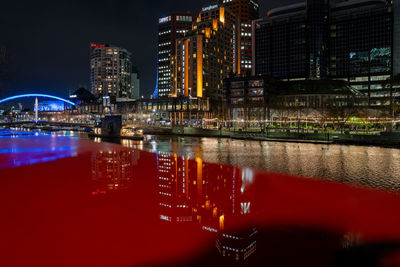 Illuminated bridge over river in city at night