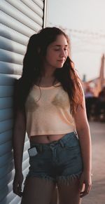 Beautiful young woman standing against white background