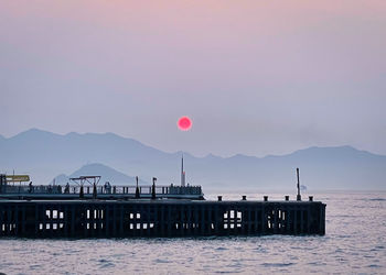 Pier over sea against sky during sunset