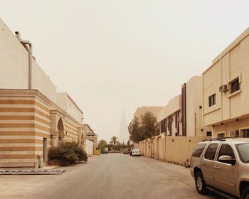 Cars on road amidst buildings against clear sky