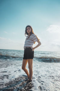 Full length portrait of young woman standing on beach