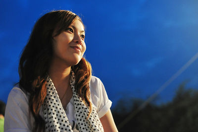 Beautiful woman looking away against sky at night