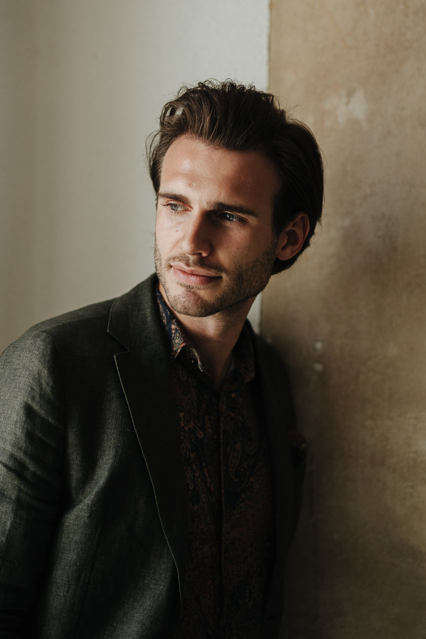 portrait, young adult, one person, young men, looking at camera, front view, real people, handsome, indoors, beautiful people, casual clothing, lifestyles, jacket, beard, wall - building feature, clothing, leather jacket, standing, leather, contemplation