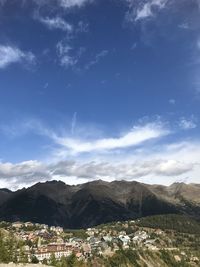 Scenic view of townscape by mountains against sky