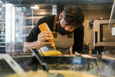 Mature male chef preparing food in commercial kitchen during covid-19