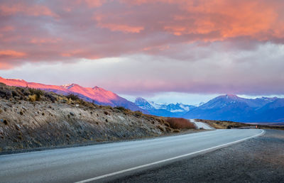 Country road and mountains against cloudy sky