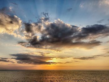 Scenic view of sea against dramatic sky during sunset