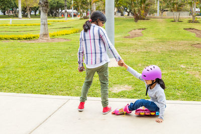 Girls giving hand to sister at park