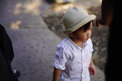 High angle view of boy wearing hat while standing on footpath