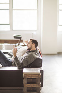 Side view of businessman gesturing and talking while sitting on sofa at office