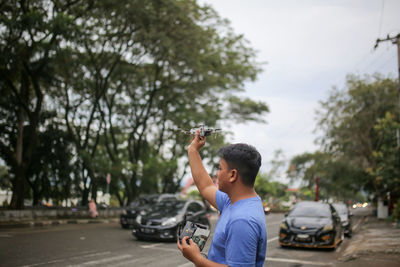 Side view of man with arms outstretched standing on road