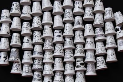 Directly above view of white cups with designs on black background