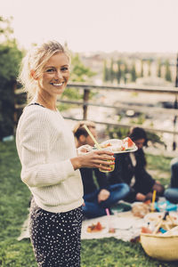 Side view portrait of happy woman holding breakfast at rooftop party