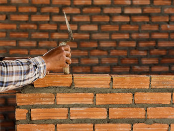 Man holding umbrella against brick wall