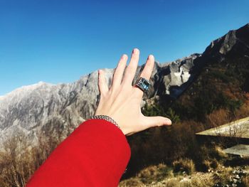 Close-up of hand wearing ring against mountains