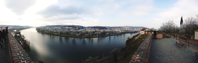 Panoramic view of city by river against sky