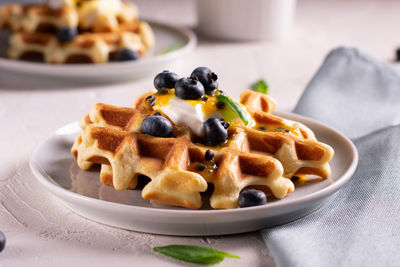 Breakfast with waffles with blueberries and syrup on a plates