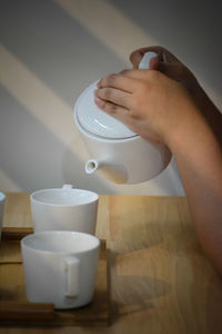 Close-up of person pouring coffee in cup