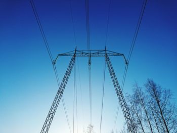 Low angle view of electricity pylon against clear blue sky