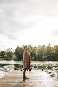 Side view of girl wrapped in towel while standing on jetty